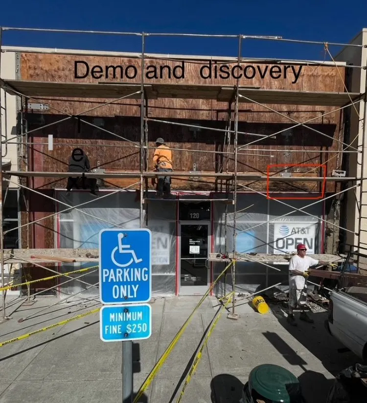 Demo and discovery phase exposing the sheathing behind the AT&T store facade — moisture infiltration investigation