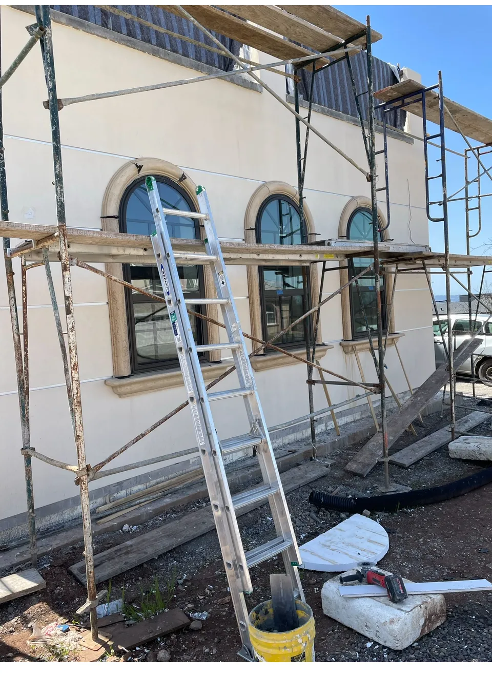 Cast stone surrounds installed on arched windows during exterior finishing — custom stonework