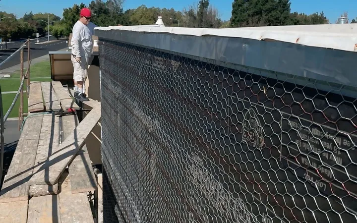 Wire lath and weather-resistive paper installed on a parapet wall ahead of stucco — waterproofing and moisture barrier work
