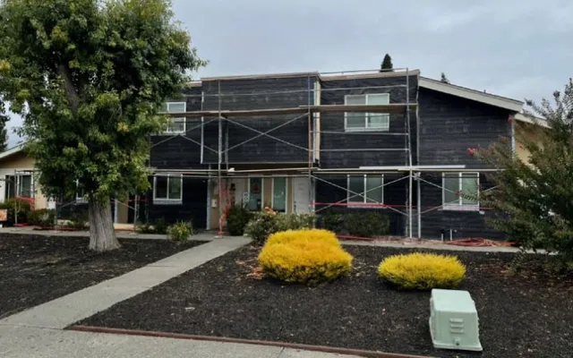 Building wrapped in weather-resistive barrier with scaffolding during a re-stucco (during) — moisture barrier installation