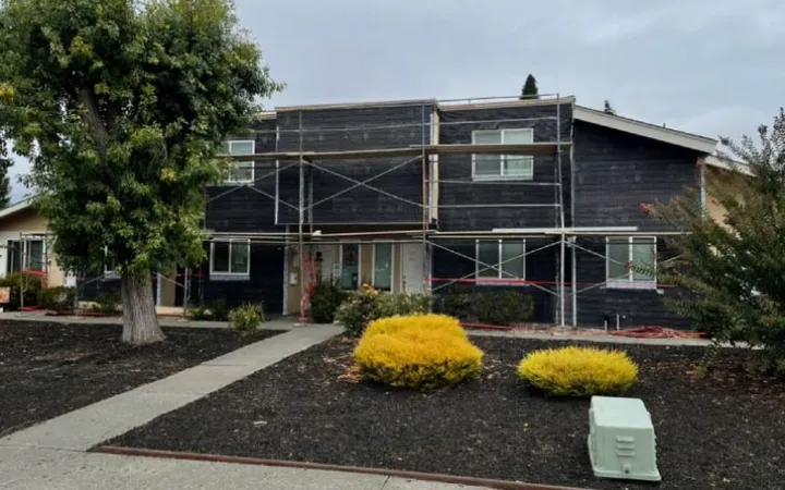 Building wrapped in weather-resistive barrier with scaffolding during a re-stucco (during) — moisture barrier installation
