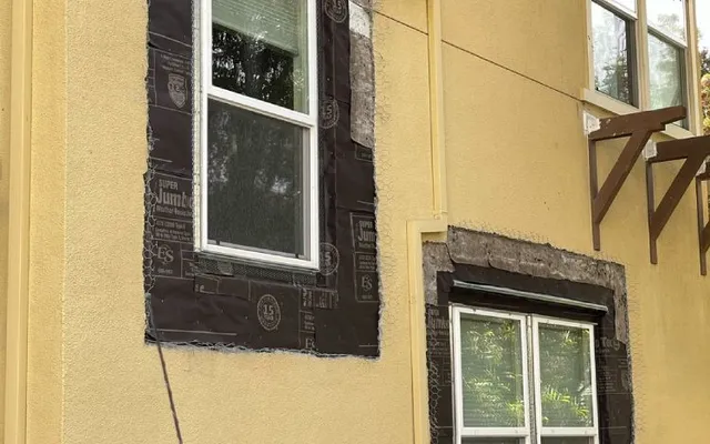 Moisture barrier paper lapped around window openings before stucco patching (during) — window waterproofing