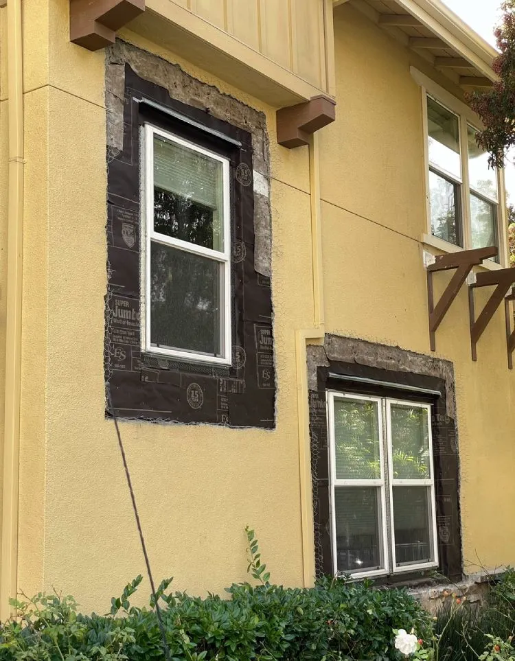 Moisture barrier paper lapped around window openings before stucco patching (during) — window waterproofing