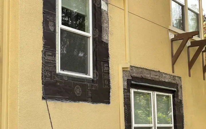 Moisture barrier paper lapped around window openings before stucco patching (during) — window waterproofing