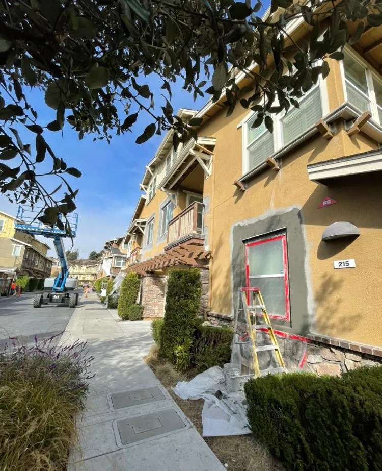 Window opening patched with fresh base coat stucco and masking on a craftsman townhome (during)