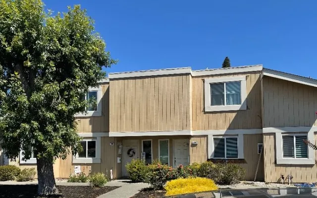 Townhome with dated vertical wood siding (before) — siding-to-stucco facade transformation