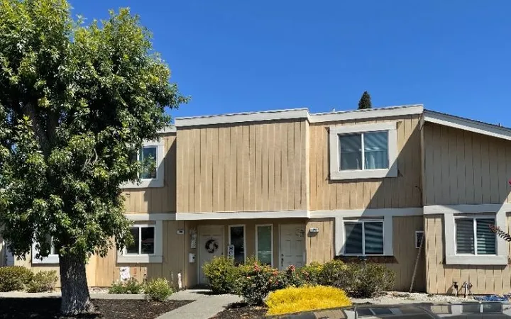 Townhome with dated vertical wood siding (before) — siding-to-stucco facade transformation
